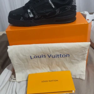 Svarta Sneakers - Snygga svarta Louis Vuitton sneakers med monogramdetaljer och vita accenter. Skorna har en chunky sula, snörning och är tillverkade i en mix av skinn och textil. Perfekta för dig som vill sticka ut med exklusiv streetstyle. Köpte de i vintras och känner att det är dags att få bort dom. Priset kan diskuteras vid snabbaffär samt tillägspris för lådan osv.