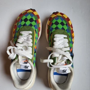 Nike x Sacai x Jean Paul Gaultier LDWaffle färgglada sneakers - Unika Nike x Sacai x JPD LDWaffle sneakers med rutigt mönster i grönt, blått, rött, gult, svart och silver. Skorna har dubbla snörningar, vit platt sula och detaljer i mocka och textil. Perfekta för dig som vill sticka ut med färg och cool design.