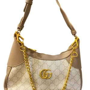 Beige axelväska med kedja - Snygg beige axelväska  med klassiskt guldfärgad kedjedetalj och logga framtill. Väskan har justerbart axelband i skinn och dragkedja upptill. Perfekt storlek för det viktigaste och ger en lyxig touch till din outfit.