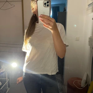 Vit t-shirt - Enkel vit t-shirt med rund hals och korta ärmar. Modellen är rak och något loose i passformen, perfekt till jeans eller shorts. T-shirten är gjord i mjuk bomull och har en klassisk look utan tryck eller mönster.