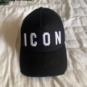 Svart keps ICON med brodyr - Svart keps från ICON med vit broderad text framtill. Klassisk böjd skärm och justerbar snapback baktill för perfekt passform. Kepsen är tillverkad i bomull och har en stilren, urban look som passar till streetwear.