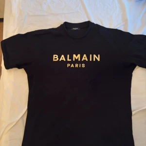 Svart Balmain Paris t-shirt i bomull - Stilren T-shirt från Balmain. Sitter grymt bra. Original såklart. Nypris över 3000kr. Slutsålda passa på sjukt bra pris för denna. Storlek L och sitter som L. 