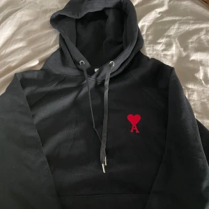 Svart hoodie från Ami med rött hjärta - Jag säljer en svart ami hoodie. Köpte den second hand. Men den var lite för stor. Så hoppas att jag typ kan få samma pengar som jag köpte den för. Jag är 185 och väger typ 75 kg. Tröjan är M men skulle säga att den sitter mer som en L. Skulle säga att tröjan är så gott som ny.