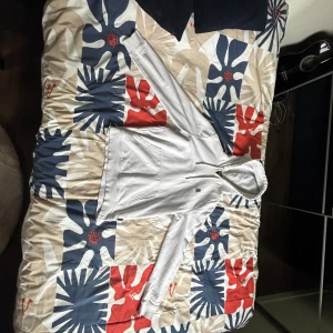 Vit hoodie med huva och ficka - Säljer en stilren vit hoodie med huva och stor magficka. Tröjan har långa ärmar och en liten svart logga på bröstet. Perfekt för dig som gillar en clean och enkel look. Materialet känns mjukt och skönt, troligtvis bomull eller bomullsblandning.