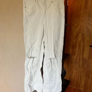 Vita wide jeans från LAB Industries - Vita jeans från LAB Industries i modell med raka, vida ben och slitningar vid knäna. Klassisk femficksdesign och normal passform. Perfekta för en clean och ljus vibe ☺️97 cm från top till tå, ca 64 cm i midjemått. Några små fläckar vid slutet av båda benen men inget man tänker på.