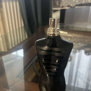 Jean Paul Gaultier Le Male Parfym - Säljer en ikonisk Jean Paul Gaultier Le Male parfym i svart, matt flaska formad som en manlig torso med blanka svarta ränder. Flaskan har en metallisk spraytopp och är tillverkad i glas. Perfekt för dig som gillar stilrena och unika doftflaskor.