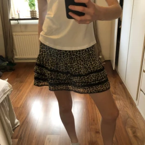 Leopardmönstrad volangkjol från Lindex - Superfin kort volangkjol från Lindex med leopardmönster i beige och svart. Kjolen har smock i midjan.