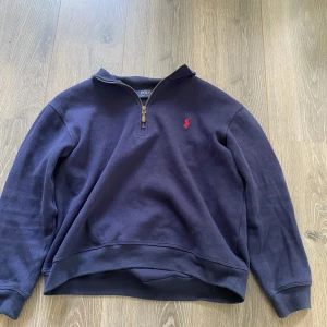 Mörkblå tröja med dragkedja från Polo Ralph Lauren - Säljer en mörkblå långärmad tröja från Ralph Lauren som är half zip, strl (S) men är mindre i modellen så passar XS, bra skick 
