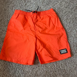 Orange badshorts från Burberry - Snygga orange badshorts från Burberry som är perfekta nu till sommaren.