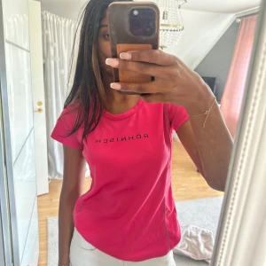 Röhnisch rosa t-shirt i funktionsmaterial - Säljer en snygg rosa t-shirt från Röhnisch med svart logga på bröstet. T-shirten är i funktionsmaterial, har korta ärmar och rund hals. 