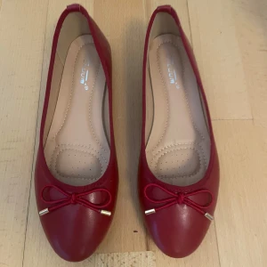 Röda ballerinaskor med rosett  - Snygga röda ballerinaskor från Adolum med rund tå och dekorativ rosett framtill med guldfärgade detaljer. Köpta från Raglady och aldrig använda. Säljer då de inte passade mig🩵