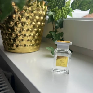 Tom Ford White Suede EdP 7,5ml - Exklusiv parfym från Tom Ford, White Suede Eau de Parfum i en stilren, genomskinlig glasflaska med vit och guldig kork. Flaskan rymmer 7,5 ml och har en lyxig känsla med sin fyrkantiga form och eleganta detaljer.