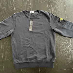 Svart tröja från Stone Island - Säljer en riktigt fet svart sweatshirt från Stone Island. Tröjan är helt ny och aldrig använd i skick 10/10. Etiketten sitter även kvar. Köpt för 1800 och säljs för 1200. Vid frågor eller funderingar är det bara och kontakta. Tröjan i storlek 170 