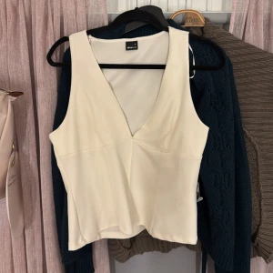 Beige v-ringad linnetopp Gina Tricot - Snygg beige topp från Gina Tricot i storlek XL. Toppen har en djup v-ringning och är ärmlös med en figurnära passform. Perfekt att styla med jeans eller kjol för en clean look. Materialet känns mjukt och följsamt. Är i fel storlek och därav inte kommit till användning 