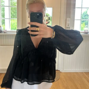 Svart volangblus från Bik Bok - Säljer en svart, transparent blus från Bik Bok med v-ringning och volangdetaljer. Blusen har långa, luftiga ärmar och en flowy passform som ger en snygg siluett. Storlek M men passar även en S.💖💖