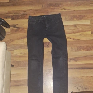 Svarta jeansbyxor från Cubus - Säljer ett par svarta jeansbyxor från Cubus med klassisk femficksdesign. Byxorna har en smal passform och normal midja. Perfekta till vardags och enkla att matcha med olika stilar.