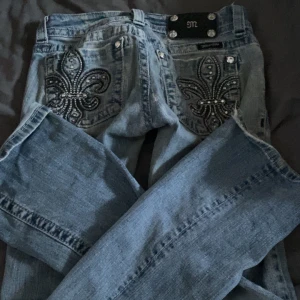 Miss me jeans - Säljer ett par ljusblå jeansbyxor från miss me med broderade detaljer och nitar på bakfickorna. Jeansen är bootcut-passform och low waist💓dom hår några skavanker som att de är lappade, skriv till mig för mer info 🫰🏻priset går att diskutera 