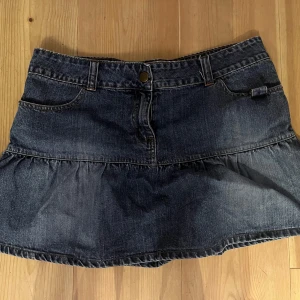 Mini jeanskjol med volang - Supercool lågmidjad jeanskjol med snygga detaljer. Använd ett fåtal gånger men i väldigt bra skick! Skulle säga att den är strl M/L, midjemåttet är 43 cm. Säljer då den är lite stor för mig. Kan tänka mig att diskutera priset💕