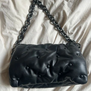 Svart väska från Zara - Säljer en svart axelväska från Zara i nyskick. Väskan har en silver/grå kedja stängs med magnetknapp. Perfekt rymlig. Skriv gärna vid frågor eller liknande😊