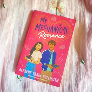 My Mechanical Romance - En ungdomsroman med romantiskt tema, där två tonåringar möts genom teknik och robotik. Omslaget är rosa med illustration av en tjej och en kille som håller i verktyg. Perfekt för dig som gillar kärlekshistorier med en nördig twist.