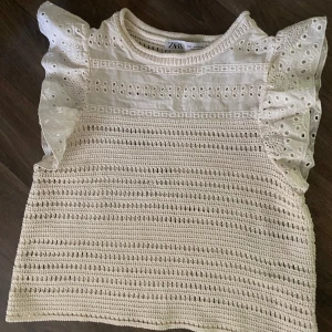 Vit virkad topp med volangärmar från Zara - Superfin vit topp från Zara med virkade detaljer och broderade volangärmar. Toppen har rund halsringning och är tillverkad i bomull. Perfekt för vår och sommar när du vill ha något luftigt och sött! Den är använd en gång så den är i princip helt ny 🤍🌸