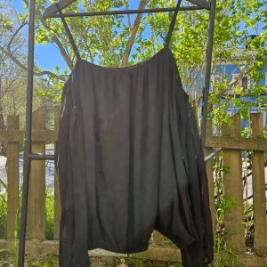 Svart långärmad blus - Säljer en svart långärmad blus med lös passform och öppna axlar. Meshtyg med undertyg över kroppen. Ärmarna är genomskinliga. 