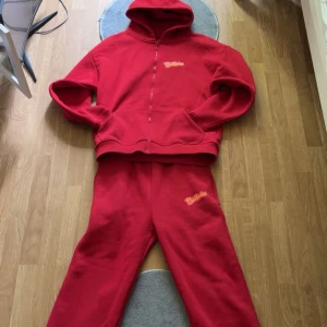 Röd hoodie från Ballerina - Säljer en röd hoodie från Ballerina med dragkedja och huva. Tröjan har tryckt Ballerina-logga i gult och rosa på bröstet och ryggen. Perfekt för dig som gillar färgstarka och bekväma plagg. Mjuk bomullskänsla och normal passform.