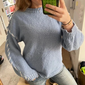 Ljusblå stickad tröja med detaljer - Jättesnygg ljusblå stickad tröja med vita sömmar. 