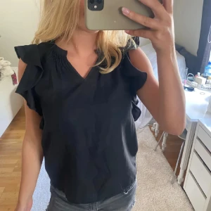 Svart blus med volangärmar - Jättefin svart blus med volangdetaljer på axlarna och v-ringning. Perfekt festtopp🩷☺️