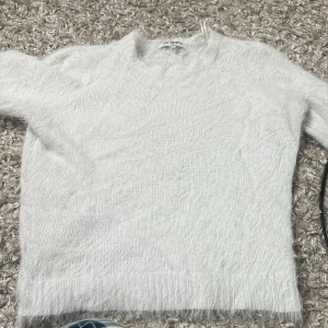 Vit fluffig stickad tröja från Love Knitwear - Supermjuk och fluffig vit stickad tröja från Love Knitwear. Tröjan har rund halsringning och korta ärmar, perfekt för lager-på-lager eller som den är. Enkel och stilren design som passar till det mesta.