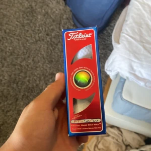  3Titleist PTS So/Lo golfbollar - Säljer en förpackning Titleist PTS So/Lo golfbollar. Förpackningen är blå och röd med vita detaljer och innehåller bollar med soft surlyn blend cover technology. Perfekt för golfentusiasten som vill ha hög kvalitet på sina bollar.