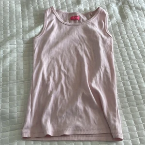 Ljusrosa ribbad linnetopp från Next - Säljer en ljusrosa ribbad linnetopp från Next. Toppen är ärmlös och har en klassisk rund halsringning. Perfekt för varma dagar eller som lager under andra plagg.