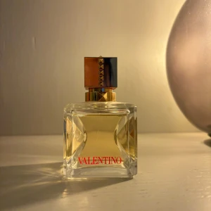 Voce Viva Eau De Parfum 50 ml från Valentino - Exklusiv parfym från Valentino i en elegant fyrkantig glasflaska med guld- och röda detaljer. Flaskan rymmer 50 ml och har en lyxig design med Valentino-loggan i rött framtill. Perfekt för dig som vill ha en ikonisk doft i samlingen. Parfymen är endast använd ett fåtal gånger.
