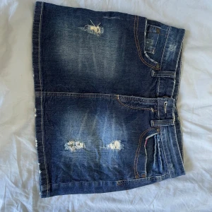 Mörkblå jeanskjol med slitningar - Snygg mörkblå jeanskjol med enkla slitningar. Storlek: 38, kan passa om du vantligvis har 36 också, märket är LINDEX