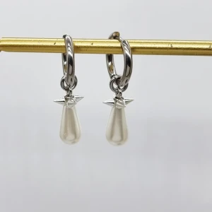 Silverörhängen med pärldroppar - Snygga örhängen i silverfärg med rund ring och hängande droppformad pärla. Ovanför pärlan sitter en liten stjärndetalj som ger extra edge. Perfekt för dig som gillar stilrena smycken med en twist.