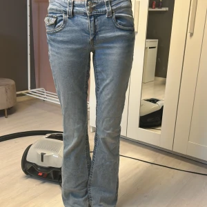 Ljusblå bootcut jeans med dubbla knappar - Säljer ett par ljusblå jeans från Gina Tricot med bootcut-modell och snygg tvätt. Jeansen har dubbla knappar i midjan & klassiska fickor! Helt nytt skick därför jag inte har använt jeansen mycket! Köpta på ordinarie pris på 359kr på Gina Young. Mycket populära jeansen där de tog slut på hemsidan direkt!