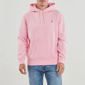 Rosa hoodie från Polo Ralph Lauren - Säljer en ljusrosa hoodie från Polo Ralph Lauren med klassisk blå logga broderad på bröstet. Tröjan har huva med vita snören och en stor magficka. Tillverkad i mjuk bomull och har en normal passform. Nypris: 2100kr
