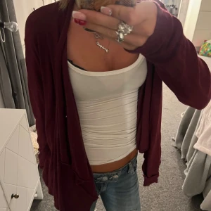 Vinröd cardigan  - Mysig vinröd cardigan jacka från Å i storlek S. Jackan är öppen framtill, har lång ärm och är tillverkad i ett mjukt stickat material. Perfekt att slänga på sig över en topp för en chill och snygg look.