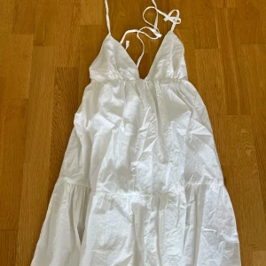 Vit långklänning med snörning STR Teen - Säljer en vit långklänning från STR Teen i storlek M. Klänningen har smala axelband, v-ringad front och snygg snörning i ryggen. Tillverkad i mjuk bomull, med volangdetaljer och luftig passform. Perfekt för varma dagar och sommarhäng.