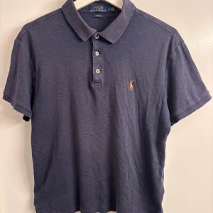Mörkblå pikétröja från Polo Ralph Lauren i Pima cotton - Snygg mörkblå pikétröja från Polo Ralph Lauren i slim fit. Klassisk krage, tre knappar och broderad logga på bröstet. Tillverkad i mjuk bomull som känns skön mot huden. Perfekt för en clean och stilren look.   Aningen krympt, sitter mer som en S-M