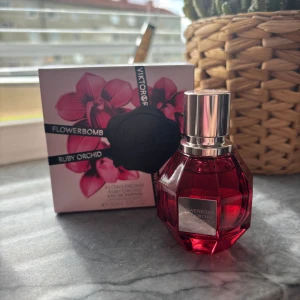 Flowerbomb Ruby Orchid parfym 30ml - Flowerbomb Ruby Orchid från Viktor & Rolf är en lyxig parfym i en snygg, facetterad röd glasflaska med silverfärgad kork. Doften är blommig och sensuell, och flaskan kommer med en matchande ask med orkidé-motiv. Perfekt för dig som gillar unika och eleganta dofter. Använd 1 gång 