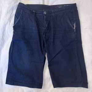 Mörkblå shorts  - Snygga mörkblå shorts med klassisk design. De har normal passform, sidofickor och två bakfickor med diskreta sömmar. Perfekta för sommardagar och lätta att matcha med t-shirt eller skjorta. Materialet känns mjukt och svalt.