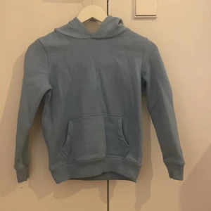 Ljusblå hoodie från Blue Ridge Denim - Säljer en stilren ljusblå hoodie från Blue Ridge Denim. Tröjan har klassisk huva, magficka och ribbade muddar vid ärmslut och nederkant. Storlek 134-140🩵