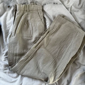 Beige linnebyxor från H&M - Snygga beige linnebyxor från H&M med normal passform och raka ben. Byxorna har hällor för bälte, snedställda fickor fram och två passpoalfickor bak. Perfekta för varmare dagar tack vare det svala linnematerialet. Använt endast 1 gång ❤️