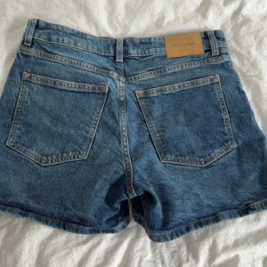Blå jeansshorts från H&M - Klassiska blå jeansshorts från H&M. Shortsens passform är normal och de har hög midja. Perfekta för varma dagar och enkla att matcha med olika toppar.byxorna är använda en gång💙