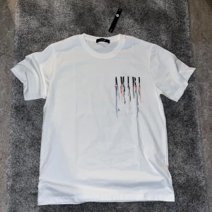 Amiri T-Shirt - AMIRI Drip Logo T-shirt. Storlek M Pris: 499 kr  AMIRI:s populära drip-logo t-shirt, passar både män och damer. Helt ny med tag kvar, aldrig använd.  Perfekt för dig som gillar streetwear men vill slippa butikens prislapp. 📦 Snabb leverans – skriv vid frågor!