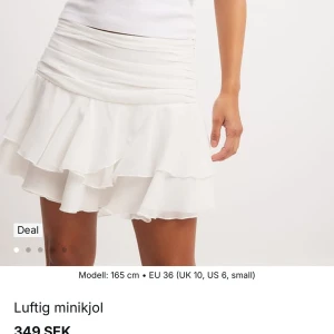 Vit volangkjol NA-KD - Säljer en luftig vit minikjol med flera lager volanger och bred, rynkad midja.  Endast använd 1 gång, storlek 34💕Originalpris: 349 kr