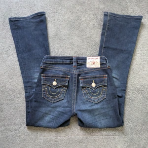 Mörkblå True Religion jeans Becca Mid Rise Bootcut - Säljer ett par mörkblå jeans från True Religion, modell Becca Mid Rise Bootcut. Jeansen har bootcut ben och de är lite uppsydda så de är inte lika långa som ett nytt par. Pris kan diskuteras💕