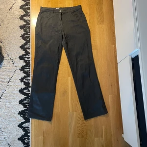 Mörkgrå byxor  - Mörkgrå byxor från KappAhl med raka ben och klassisk passform. Tillverkade i en bomullsblandning med polyester och lite lycra för stretch. Byxorna har knapp och dragkedja framtill samt fickor både fram och bak. Sitter som ett par kostymbyxor. Storlek 38