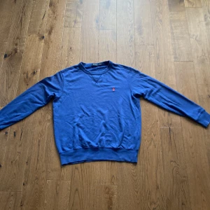 Blå sweatshirt från Polo Ralph Lauren - Säljer en blå sweatshirt från Polo Ralph Lauren. Den är i bra skick o riktigt snygg. Den är välanvänd så den är lite nopprig. Bra kvalite och väldigt skön att ha på sommaren. Har du några funderingar hör av dig.
